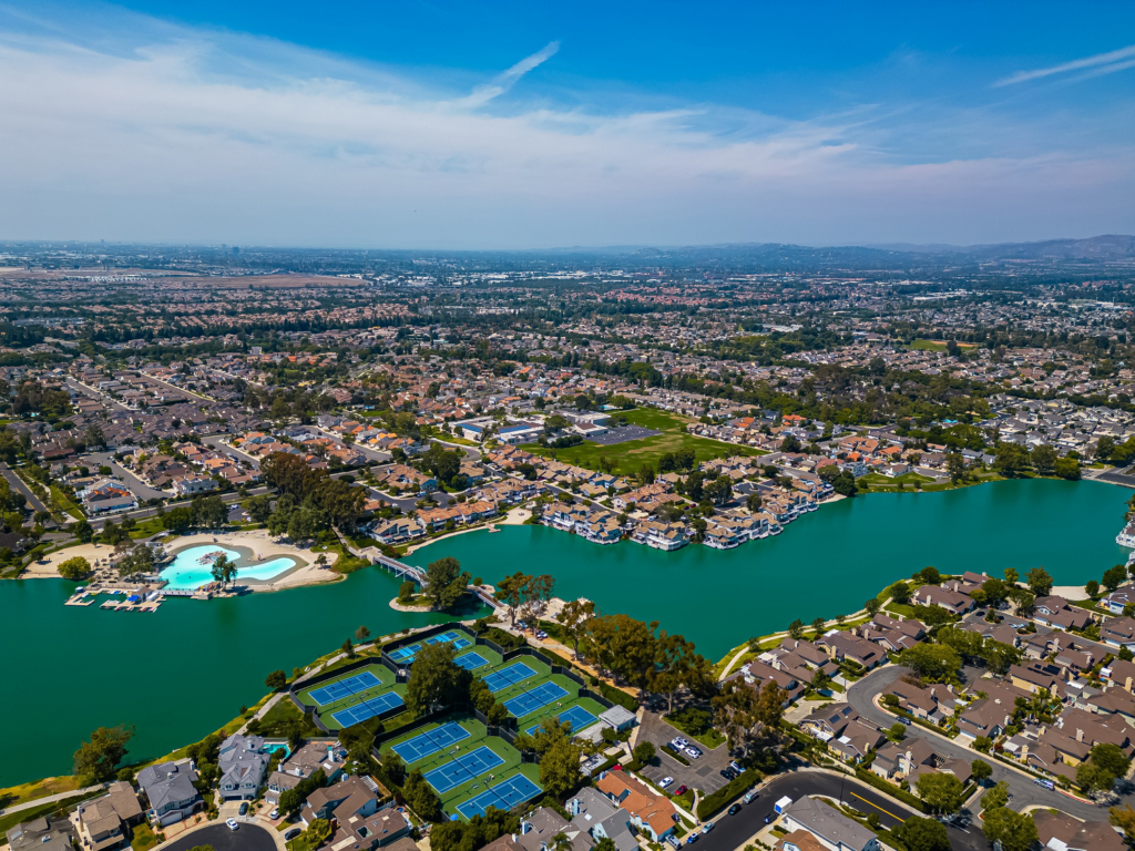 Woodbridge Irvine lake with surrounding condos, townhomes, tennis courts, and sandy beach